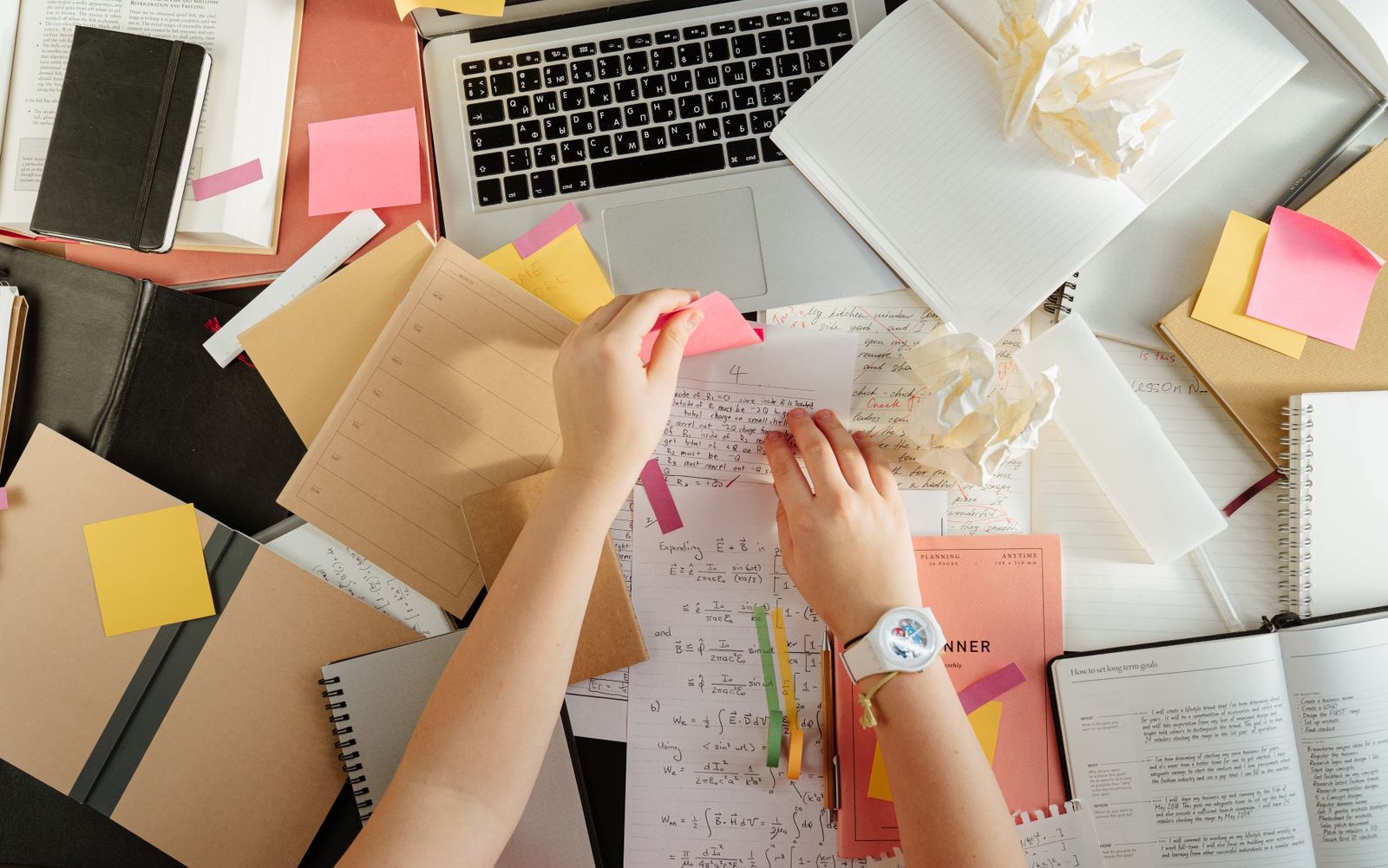 A desk buried in files, sticky notes and notices